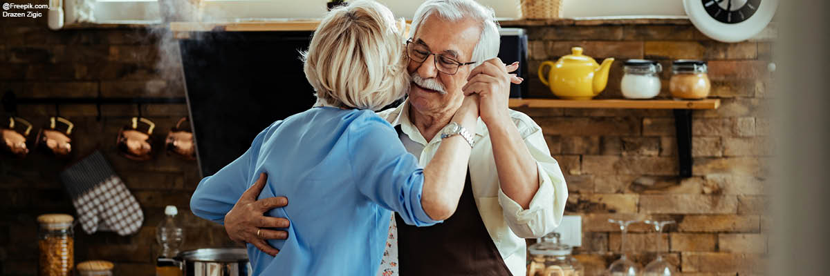 coppia anziana che si abbraccia in cucina